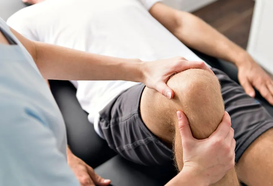 Physiotherapeutische Behandlung eines Knies auf der Liege